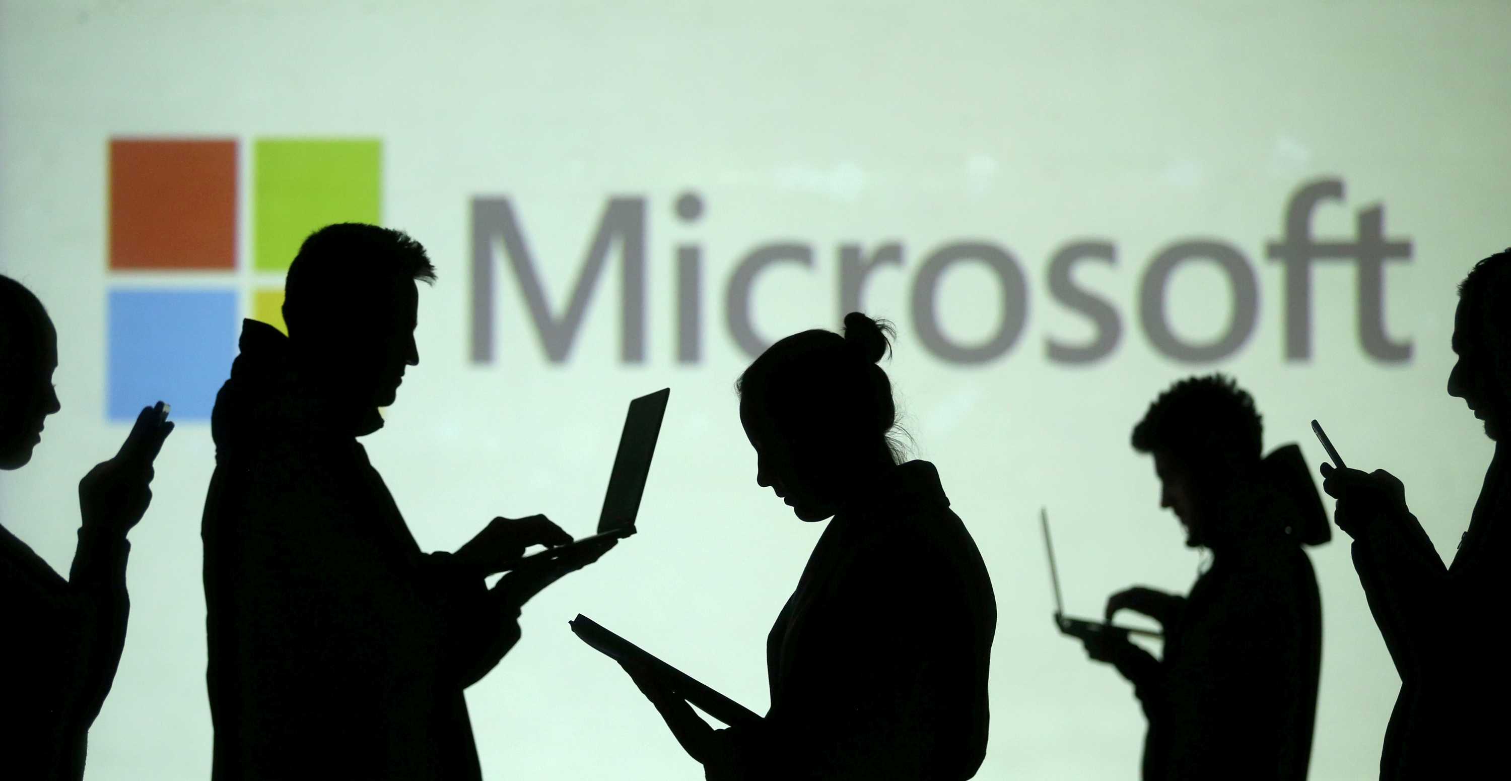 笔记本电脑和移动设备用户的剪影出现在屏幕旁边Microsoft 徽标投影